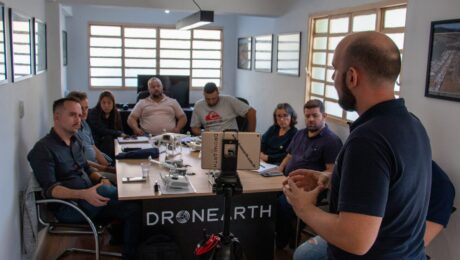 Aula teórica na escola de drones da Dronearth Turma em aula teórica na escola de drones da Dronearth, com drones sobre a mesa e instrutor à frente