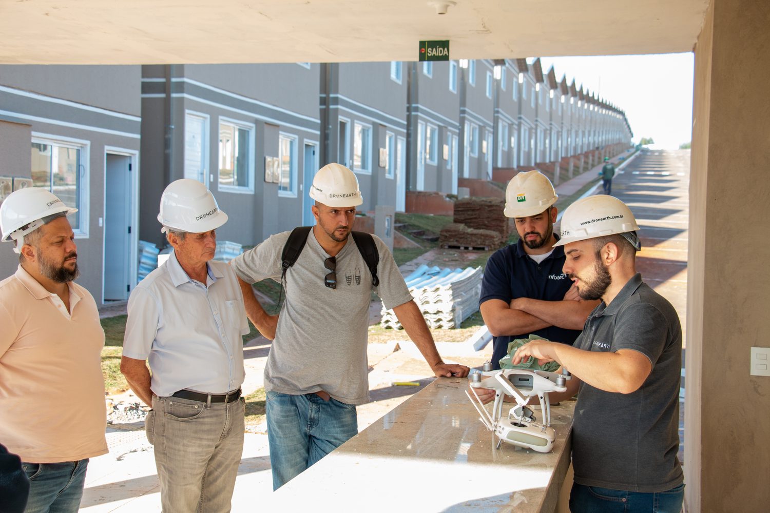 Instrutor da Dronearth apresenta um drone a equipe de capacete em canteiro de obras